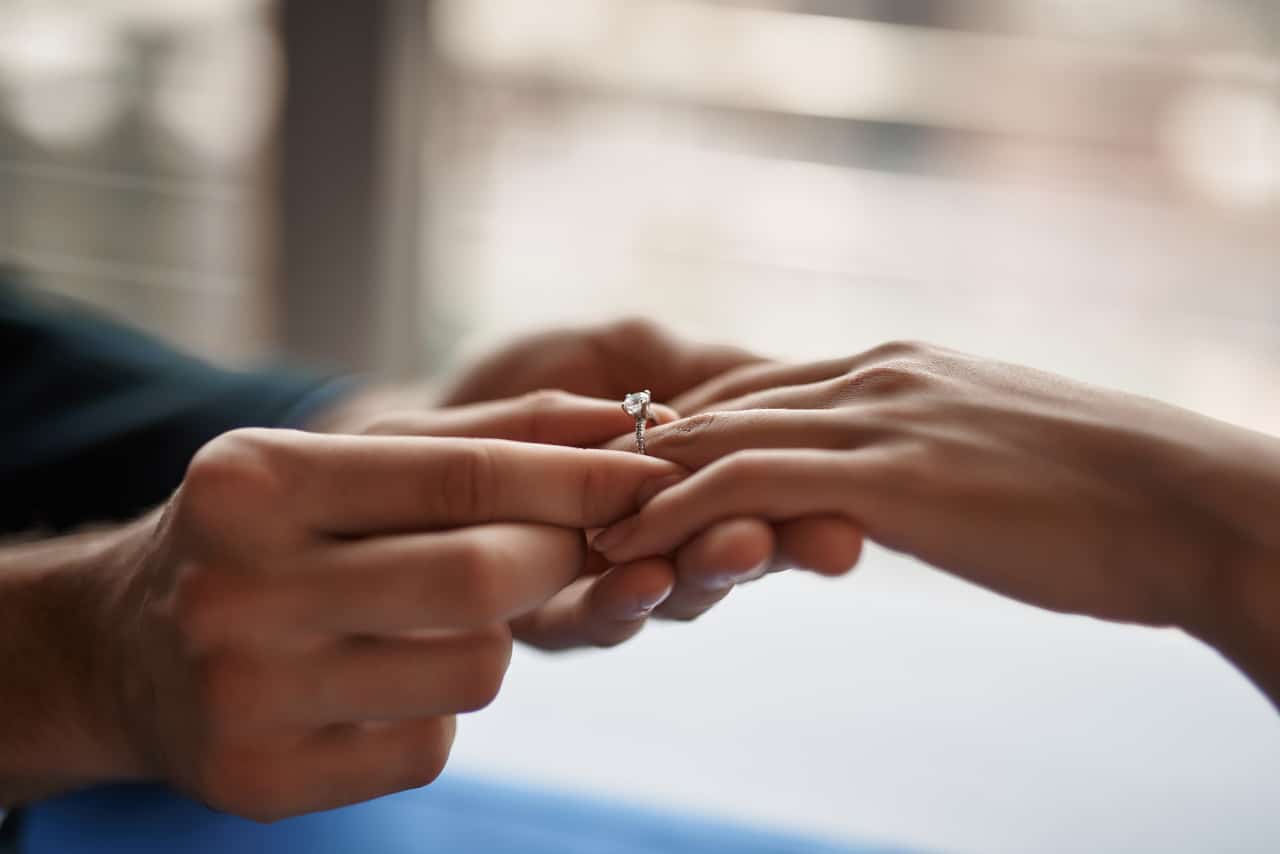 Concept of engagement. Close up portrait of young gentleman putting ring on finger of his beloved woman